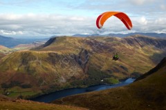 Paraglider soaring over Buttermere valley - looking east from Red Pike