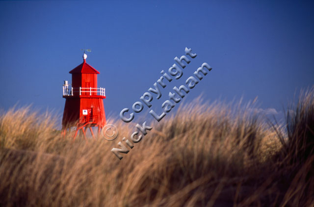 red sand dune grass blue sky tower coast sea